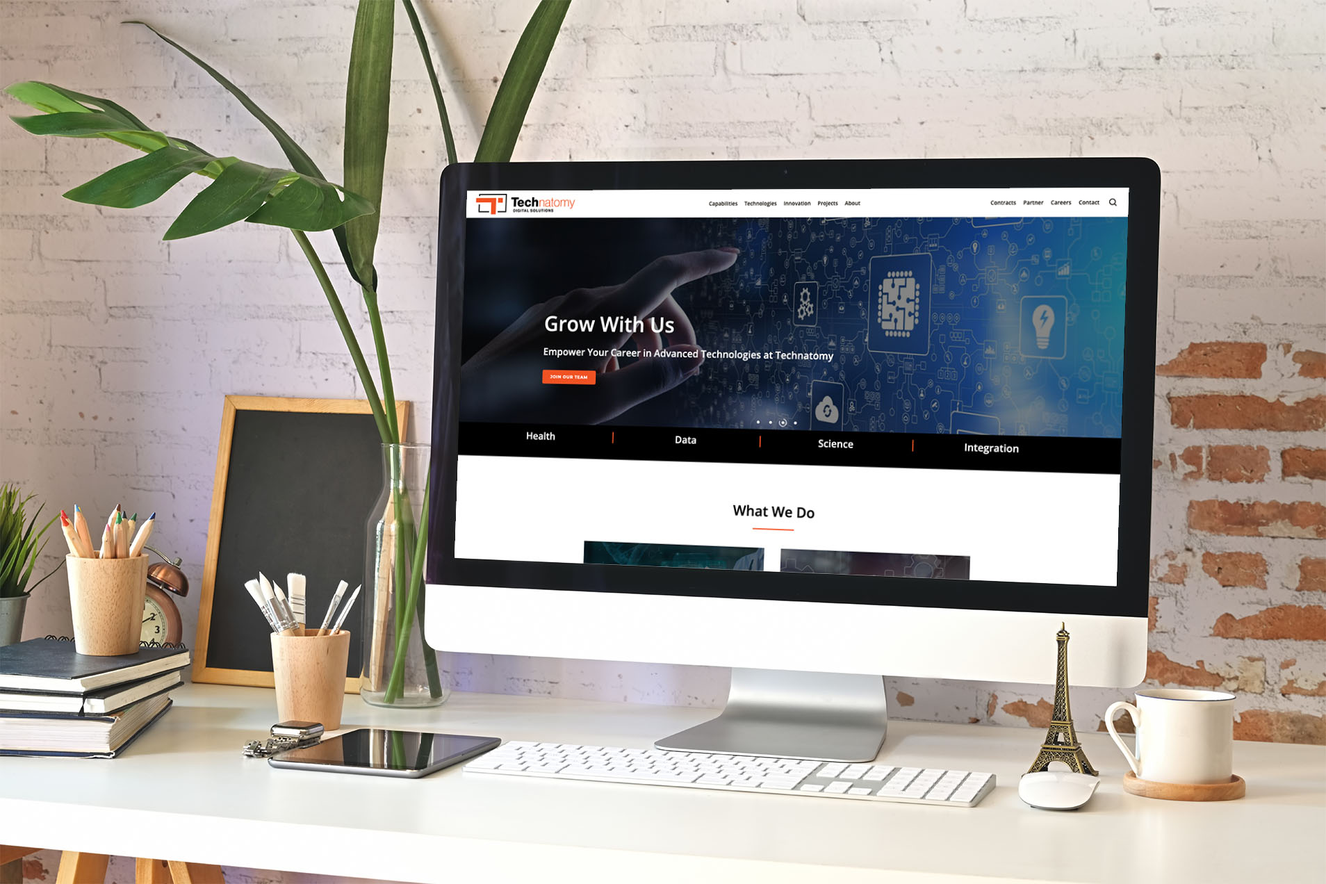 Technatomy homepage displayed on a desktop monitor, featuring the Grow With Us hero and technology imagery